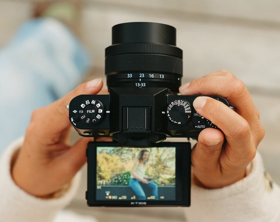 Cầm máy ảnh Fujifilm X-T30 III chụp ảnh cận cảnh trên nền sáng tự nhiên