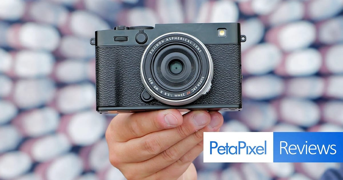Cầm máy ảnh Fujifilm X-E5 góc cận cảnh trên nền vải họa tiết