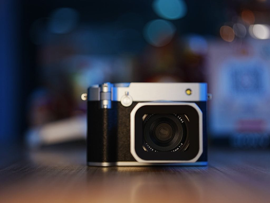 Chiếc máy ảnh Fujifilm GFX100RF được đặt trên mặt bàn gỗ với hậu cảnh mờ ảo