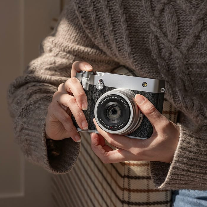Cầm máy ảnh Fujifilm GFX100RF góc cận cảnh trong không gian ấm cúng