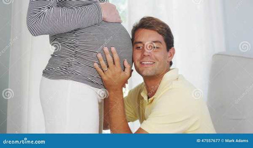 dad listening to pregnant wife s belly husband home 47557677.jpg