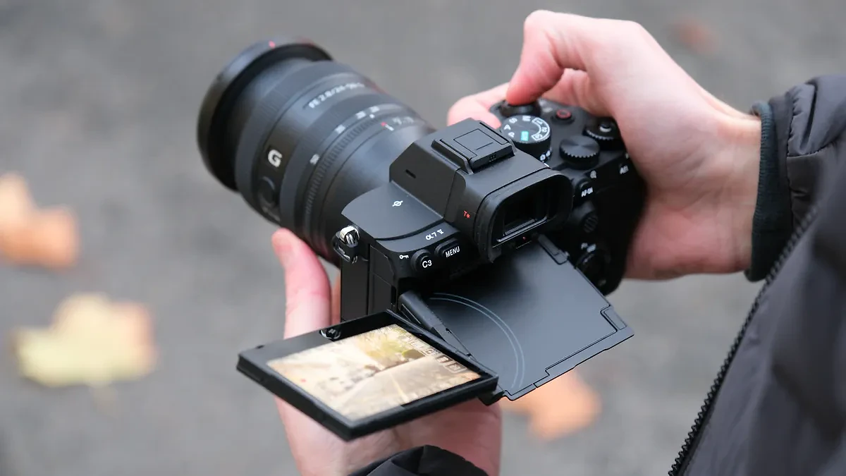 Sony A7 V camera held in a person's hands with the screen folded out