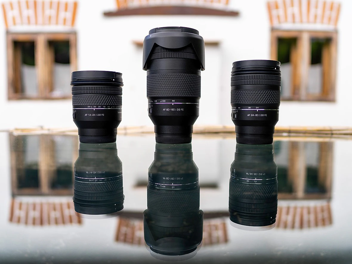 three lenses are on a reflective surface with a white building behind