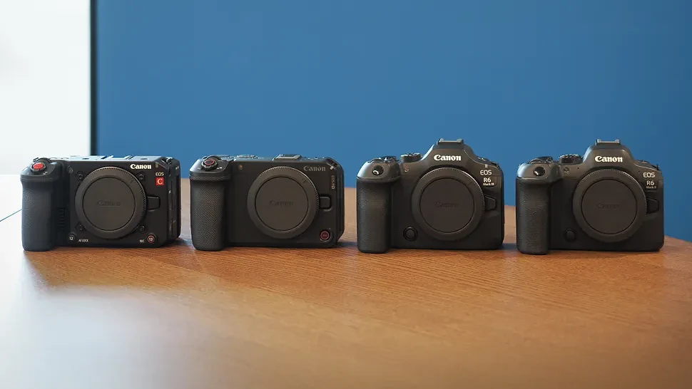 The Canon EOS C50, R6 V, R6 Mark III and R6 Mark II on a wooden surface, against a blue background