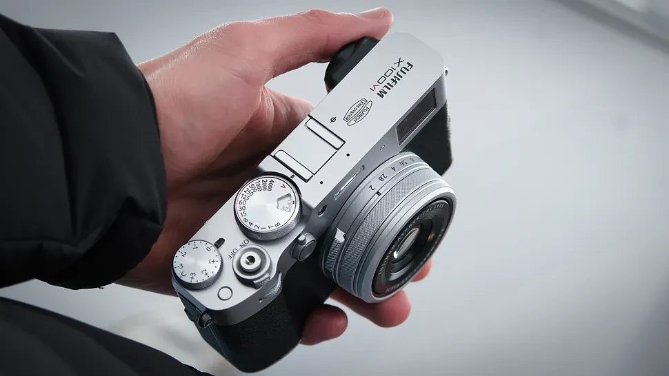 Man holding a Fujifilm X100 VI compact camera in one hand
