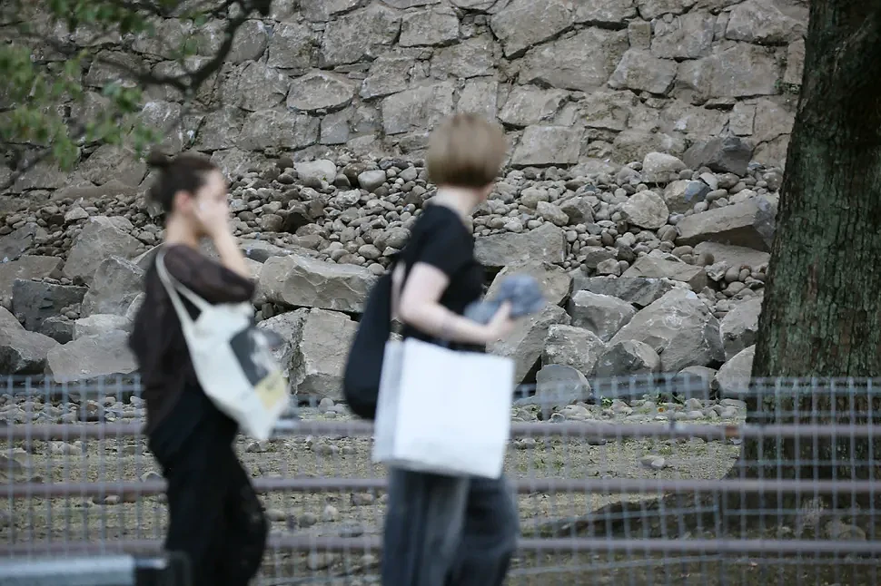 People walk near the collapsed stone walls of Kumamoto Castle after an earthquake, at Chuo Ward in Kumamoto, on July 28, 2026. A major earthquake collapsed buildings and sparked fires in Japan's southwest, Prime Minister Sanae Takaichi said, with broadcaster NHK saying that at least 50 people were taken to hospital. (Photo by JIJI Press / AFP) / Japan OUT