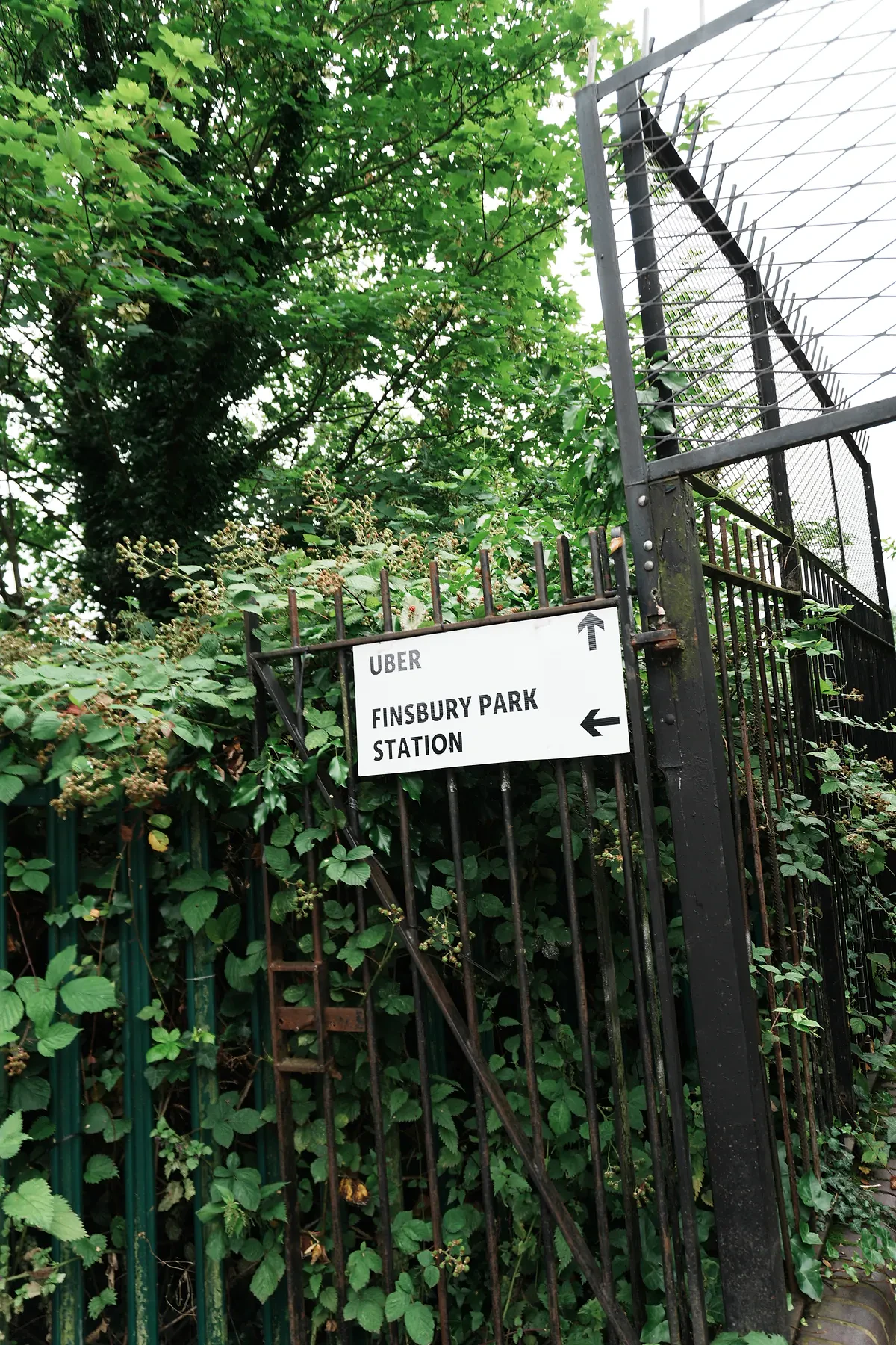 A sign showing directions on a fence in front of a tree