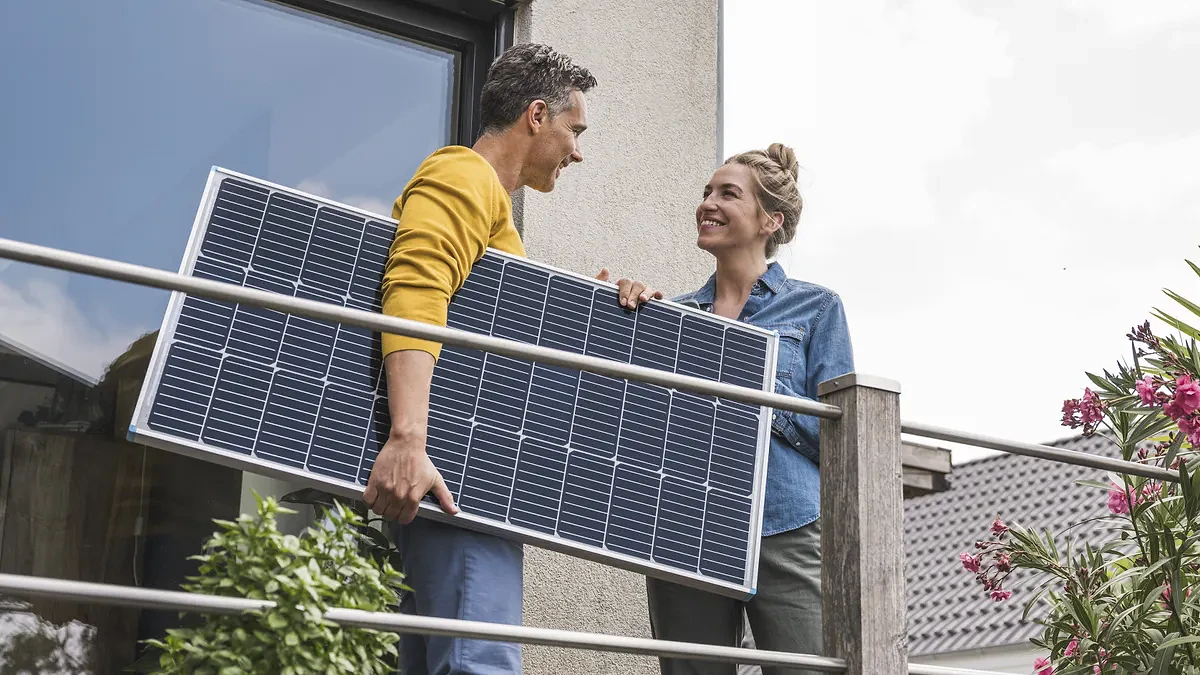 Couple standing on balcony holding solar panel