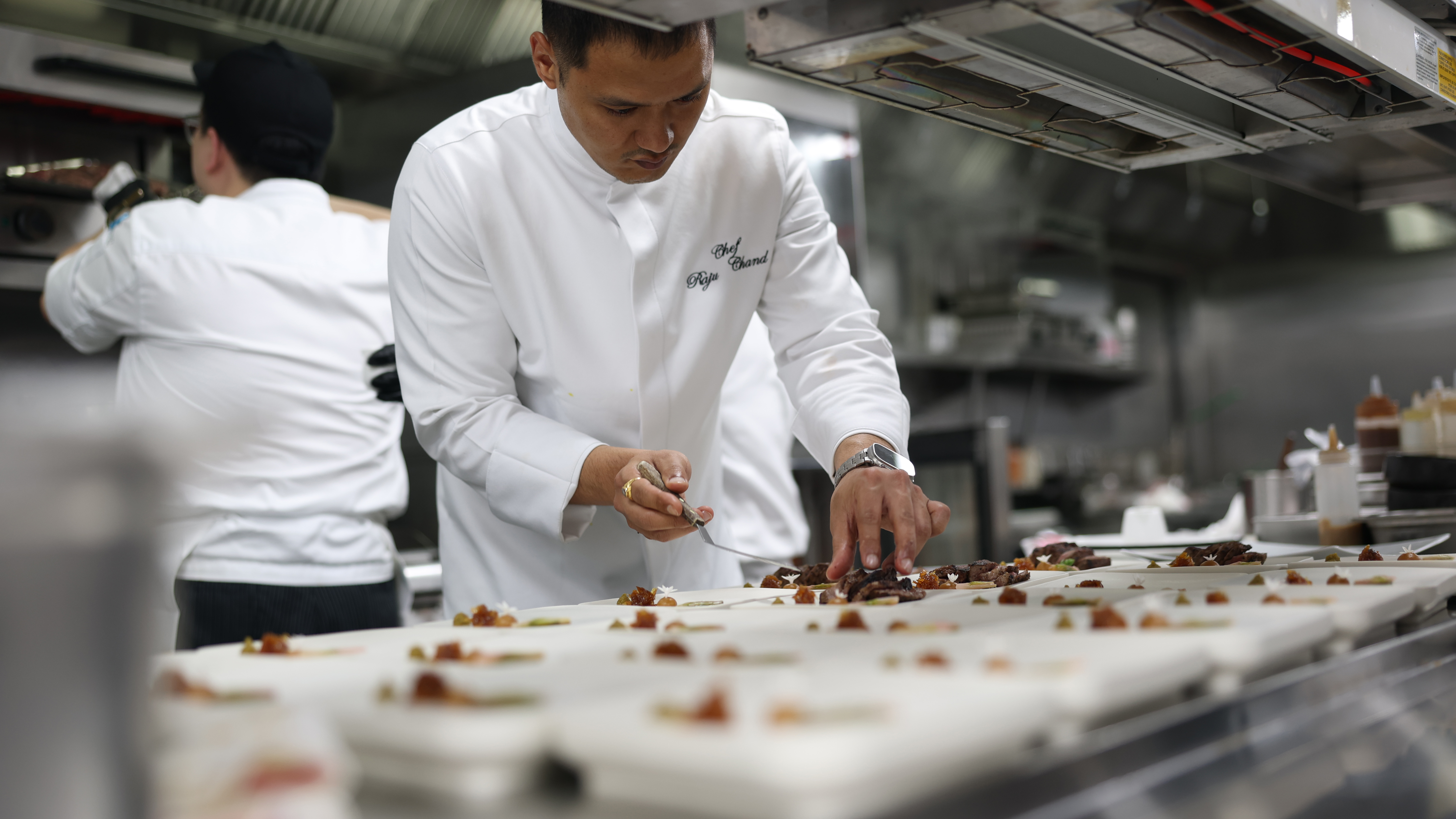 Chef preparing a course for the Refine Dining tasting menu