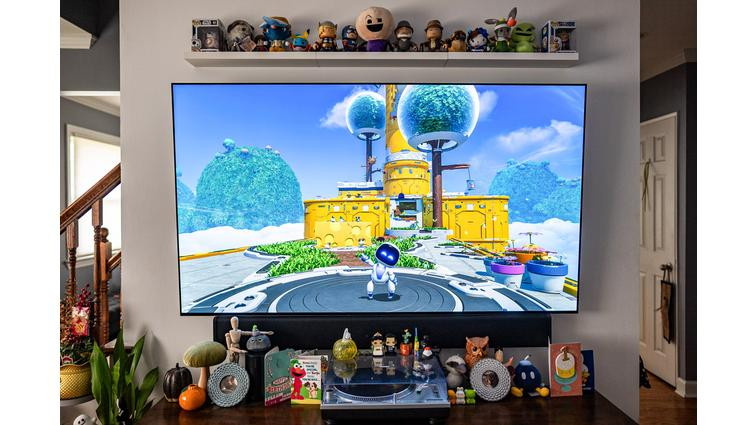 A TV set with a game on it, small figures lined up on a shelve above and a table top below.