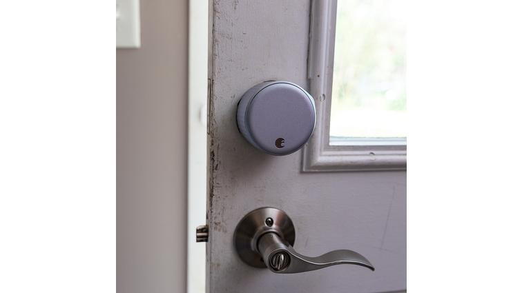 None A large silver door lock on a door above a lever handle