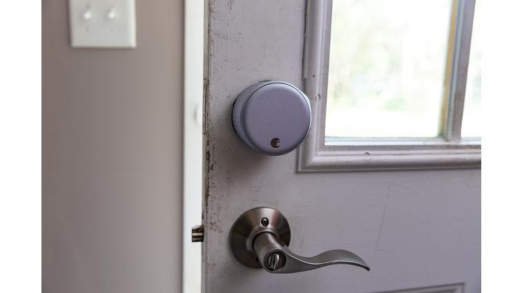 A large silver door lock on a door above a lever handle