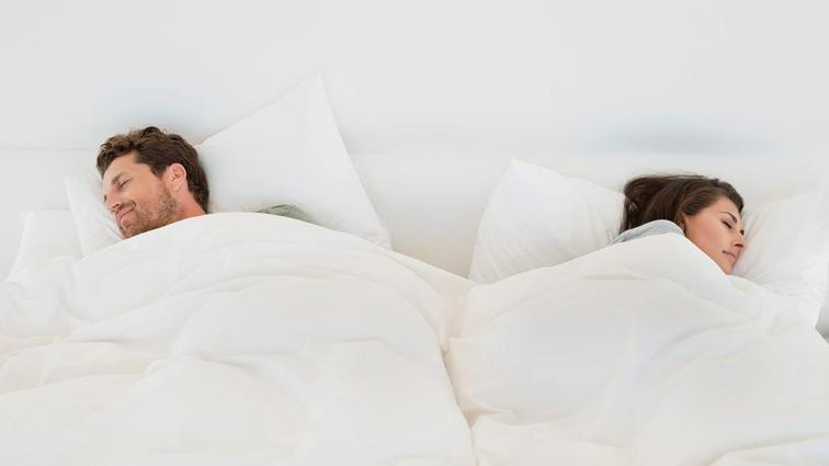 Homem e mulher dormindo com cobertores separados