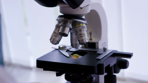 serious clinician studying chemical element in laboratory close up of microscopic lens SBI 350792073.jpg