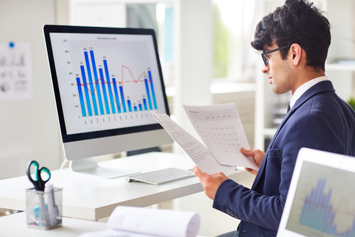 Businessman looking through papers by workplace and analyzing statistics.jpg