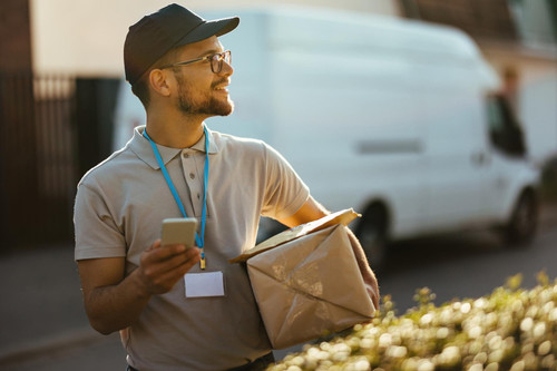 young happy courier using smart phone while making delivery residential district 637285 2310.jpg