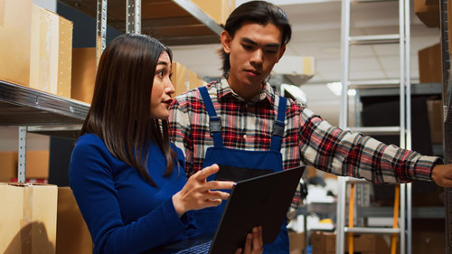 warehouse employees working inventory with laptop walking around storage room racks with carton boxe.jpg