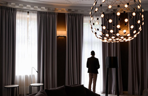 man looking outside modern room with gray curtains hanging lamp 8353 12543.jpg