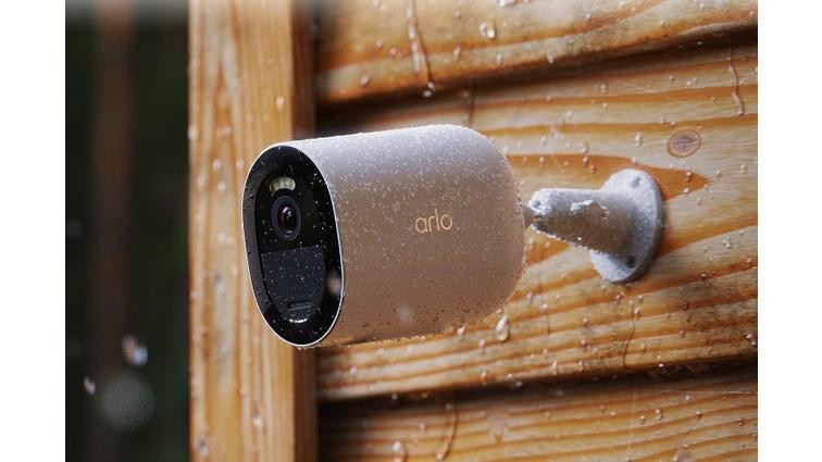 None Arlo's Go 2 camera mounted on wooded exterior siding in the rain.