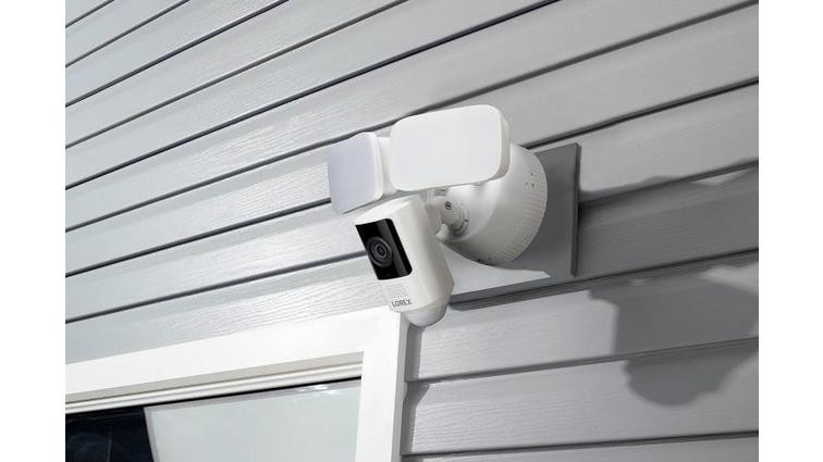 None The Lorex floodlight cam mounted on house siding above a glass door.