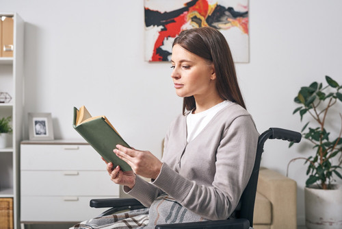 young disable brunette woman casualwear sitting wheelchair reading book while spending day home 2746.jpg