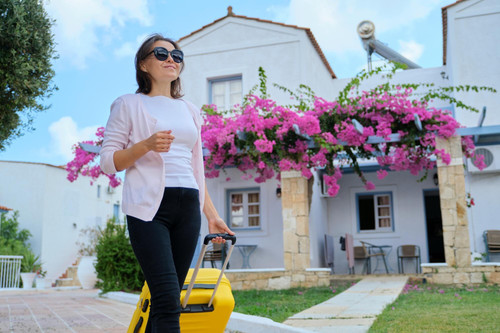 beautiful woman tourist walking with suitcase territory resort spa hotel white blue hotel houses blo.jpg