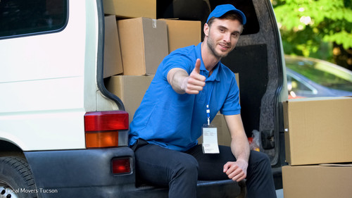 Moving company worker showing thumbs up, sitting in van full of cardboard boxes.jpg