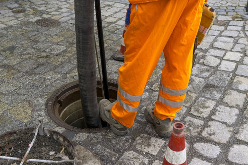 sewerage worker on street cleaning pipe.jpg