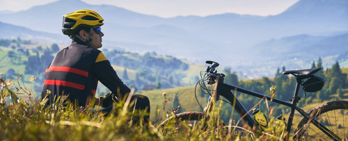 man cyclist sitting grass looking mountains.jpg