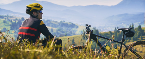 man cyclist sitting grass looking mountains.jpg