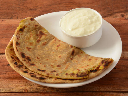 Aloo Paratha or Indian Potato stuffed Flatbread. Served with fresh curd. isolated over a rustic wood.jpg