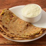 Aloo Paratha or Indian Potato stuffed Flatbread. Served with fresh curd. isolated over a rustic wood