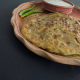aloo paratha with curd served on plate. Traditional north indian food. Shot in black background.
