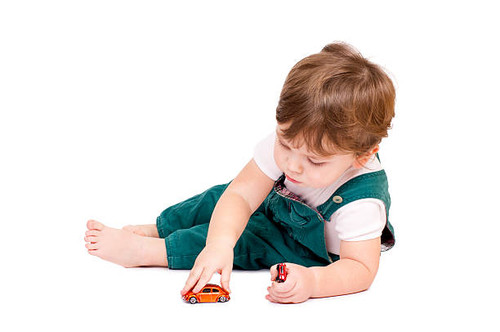 Little cut boy playing with two toy cars. Isolated on white..jpg
