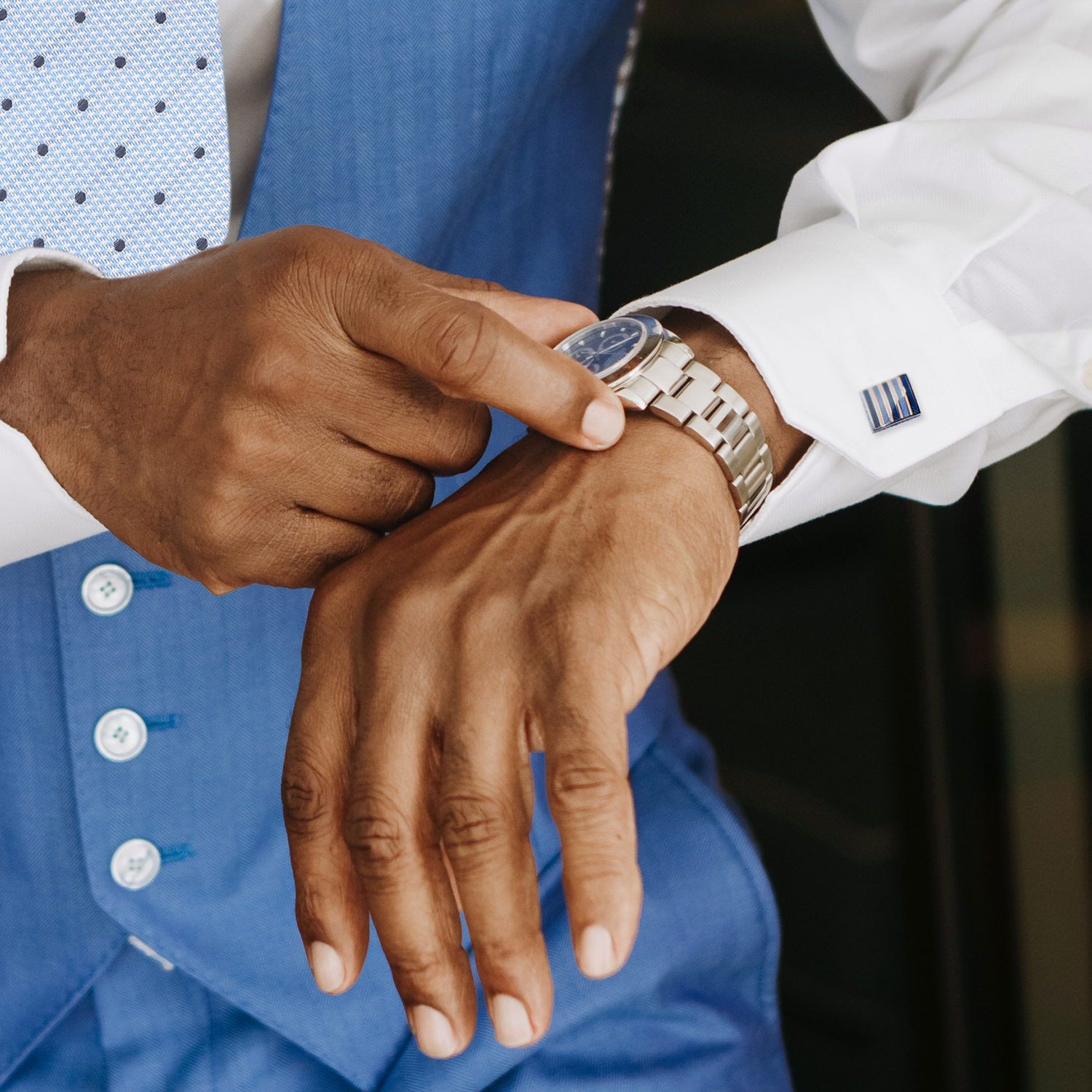 African American groom adjusting watch with cufflinks on