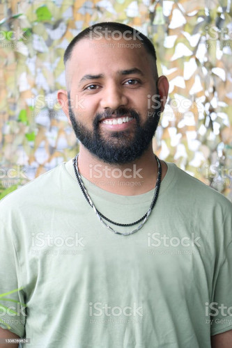 Stock photo showing headshot of Indian man with shaved head wearing t-shirt and necklaces..jpg