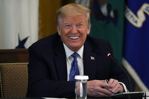 President Donald Trump smiles as he holds a debit card handed to him by Treasury Secretary Steven Mn