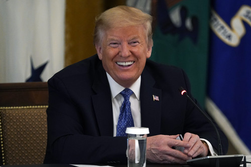 President Donald Trump smiles as he holds a debit card handed to him by Treasury Secretary Steven Mn.jpg