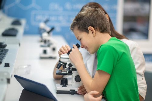 boy looking through microscope near sitting teacher 1024x681.jpg