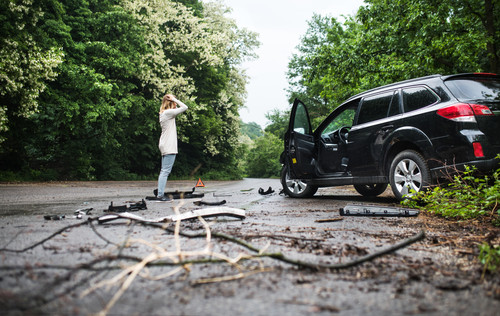 Young frustrated woman standing by the damaged car after a car accident..jpg