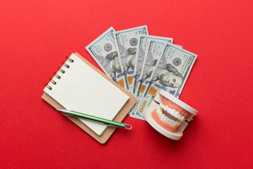 Flat lay composition with educational dental typodont model and money with notebook on colored table.jpg
