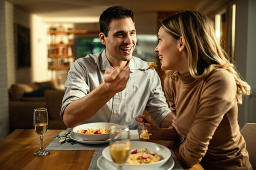 happy couple having fun during meal dining table man is feeding his girlfriend.jpg