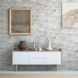 Front view of burlap artworks on a light gray wall above a wooden cupboard with decorations in real 