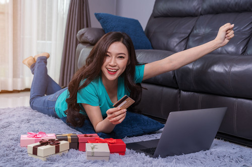 cheerful woman using laptop to successful shopping online with credit card in the living room.jpg