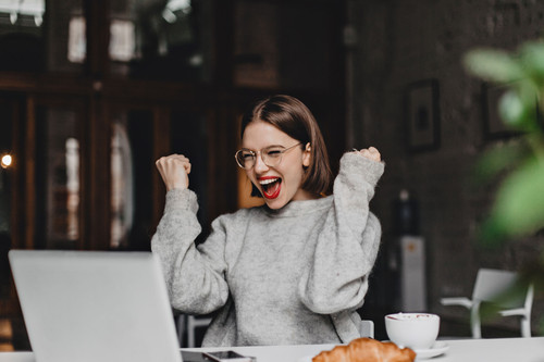 Happy woman in glasses makes winning gesture and sincerely rejoices. Lady with red lipstick dressed .jpg