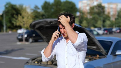 Young man using smartphone by broken-down car in the city. Car repair. Transport and lifestyle conce.jpg