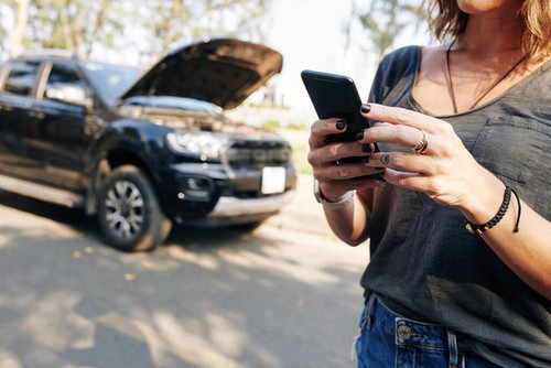 Cropped image of young woman using mobile application to connect car service.jpg
