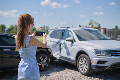 Stressed driver taking picture on sellphone camera of smashed vehicle calling for emergency service .jpg