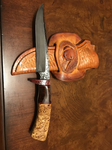 Bird and trout knife. Brut de forge 1095 blade with hamon. Red oxidized copper guard, domed copper pins. Handle is desert ironwood, maple burl, with G10 spacers. Tooled leather sheath with pintail drake.