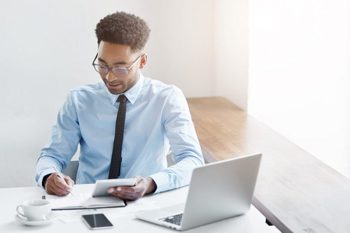 successful young male dark skinned accountant with afro hairstyle and bristle using digital tablet .jpg